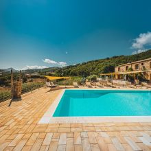 Outdoor swimming pool and historic farmhouse surrounded by greenery