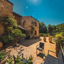 Stone farmhouse surrounded by Mediterranean gardens and trees