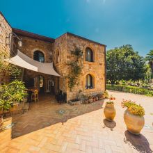 Historic stone building surrounded by lush Mediterranean gardens