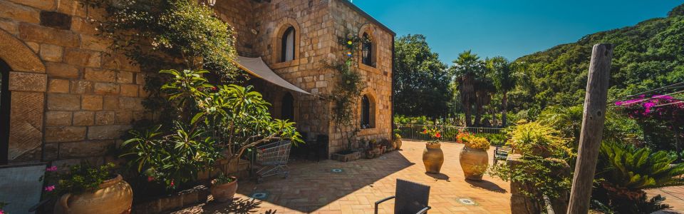 Stone farmhouse surrounded by Mediterranean gardens and trees